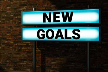 Obraz premium New goals. Black letters on a light box. Illuminated sign in front of a red brick wall. Business, motivation, chance, inspiration, new plans, checklist, be ready and determine. 3D illustration