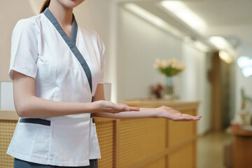 Cropped image of spa salon receptionist welcoming clients inside