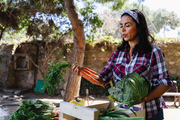 Pretty latin woman placing freshly picked vegetables from the garden