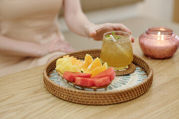 Cup of iced tea and fresh fruits on tray in front of spa salon client