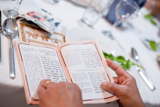 Man's hands holds book. Holiday of Jewish people, Matzo national food served on  table on special plate. Traditionally Passover celebrate with red wine. Israel, april, 05, 2023