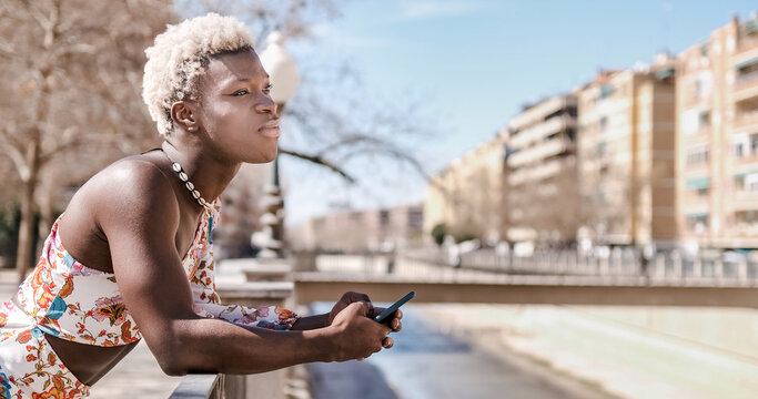 Annoyed black queer man messaging on smartphone on street