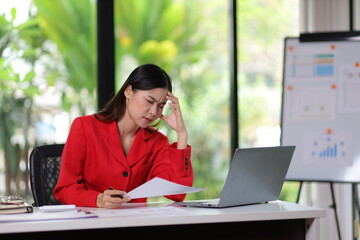 Serious Asian businesswoman in the office having a headache and tired overwork.