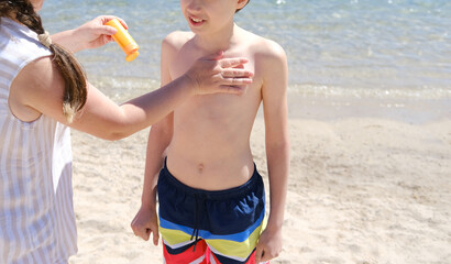 happy cool child, brunette boy 11 years old in shorts stands on seashore, takes sunbaths, woman,...