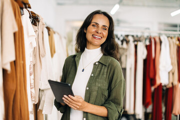 Happy boutique owner using a tablet to manager her shop