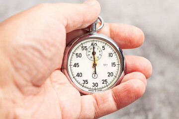 stopwatch in hand on a gray background