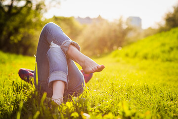 girls legs lying on the grass at sunset time. Spring vacation relax concept