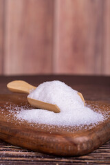 White refined sugar on wood background. Close-up of granulated sugar in wooden spoon
