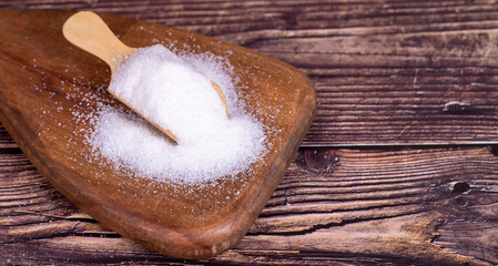 White refined sugar on wood background. Powdered sugar in a wooden spoon. Copy space. Empty space for text