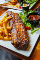 Delicious and appetizing barbecue grilled rib with chips and sauce, in a Belgian restaurant.