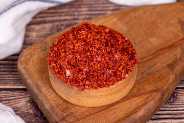Chilli pepper seedless flakes in wooden bowl. Spices and food ingredients. Close up