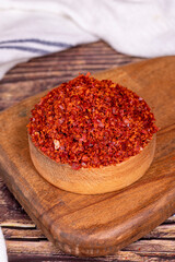 Chilli pepper seedless flakes in wooden bowl. Spices and food ingredients. Close up
