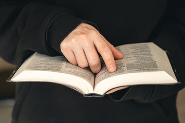 Fototapeta premium Open book Bible in male hands, close-up.