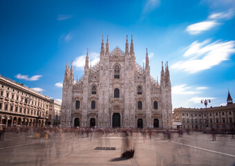 Fototapeta na wymiar Long time exposure of Milan cathedral (Duomo di Milano) front on a sunny day with people moving across the square