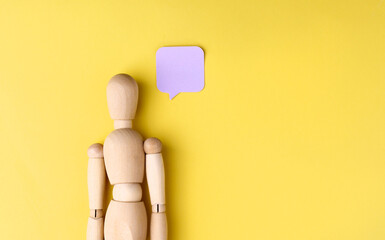 Wooden mannequin is pretending to think something on yellow background with copy space.