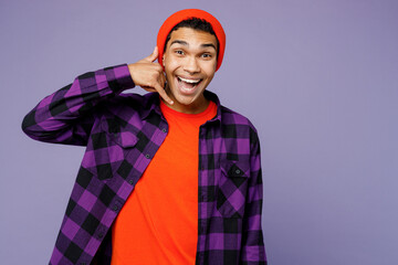 Young excited happy man of African American ethnicity wears casual shirt orange hat doing phone gesture like says call me back isolated on plain pastel light purple color background studio portrait.