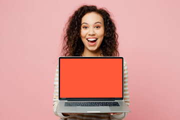 Young IT woman of African American ethnicity wear light casual clothes hold use work on laptop pc computer with blank screen workspace area isolated on plain pastel pink background studio portrait.