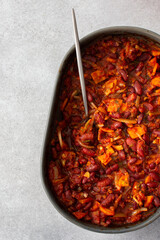 Healthy breakfasts and lunches, stewed red beans with carrots, onions and tomatoes, top view of an oval ceramic roaster with stewed legumes