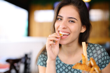 Happy woman eating chicken fingers in a restaurant - obrazy, fototapety, plakaty