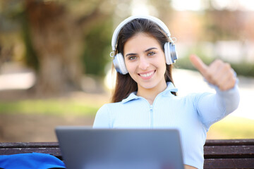 Student with laptop and headphones with thumbs up