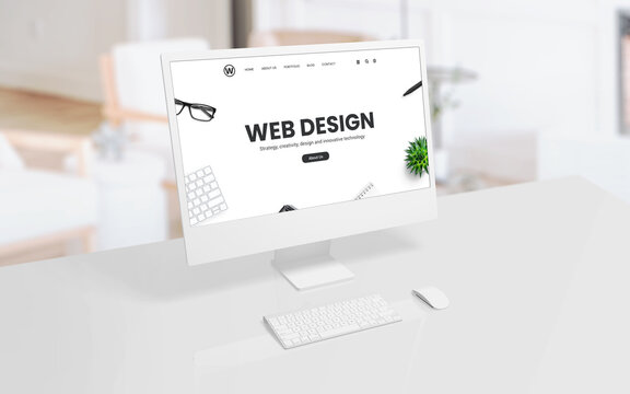 White computer display on an office or studio desk with a web design concept web page on the screen. Modern technology, creative design, and productivity concept