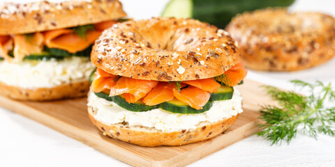 Bagel sandwich with salmon and cream cheese for breakfast on a kitchen board panorama