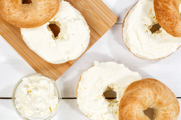 Bagel sandwich with cream cheese for breakfast from above on a wooden board
