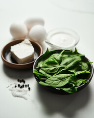 Close up of iingredients for healthy spinach and feta omelette. Eggs with heavy cream, Fresh baby...