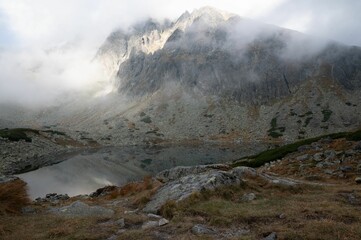 Clean, tranquil lake on top of the mountain surrounded by massive rocks and stones