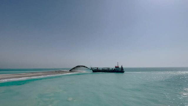 Creation of an artificial island. The construction ship pours sand on the island