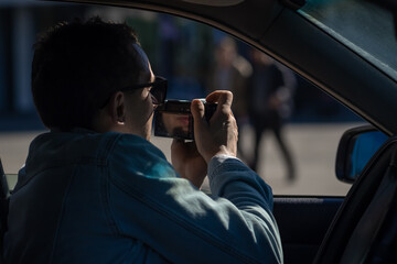 Paparazzi men or guy in sunglasse sits in her car and takes pictures of famous person.Spy with...