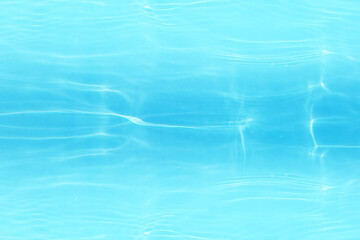 Bluewater waves on the surface ripples blurred. Defocus blurred transparent blue colored clear calm water surface texture with splash and bubbles. Water waves with shining pattern texture background.