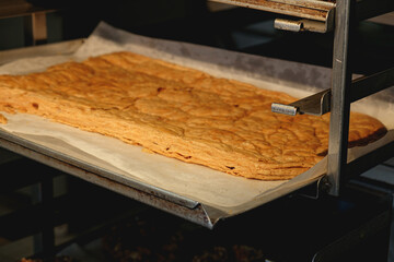 Freshly baked Napoleon pastry cakes cooling on a baking sheet in a cozy kitchen setting early in...