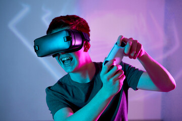 Young man wearing VR glasses playing video game in front of wall