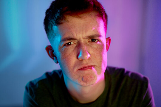 Young man with facial expression with illuminated neon light on face