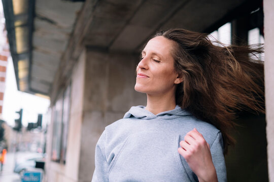 Smiling woman with eyes closed tossing hair