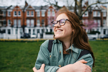 Cheerful young woman wearing eyeglasses hugging self