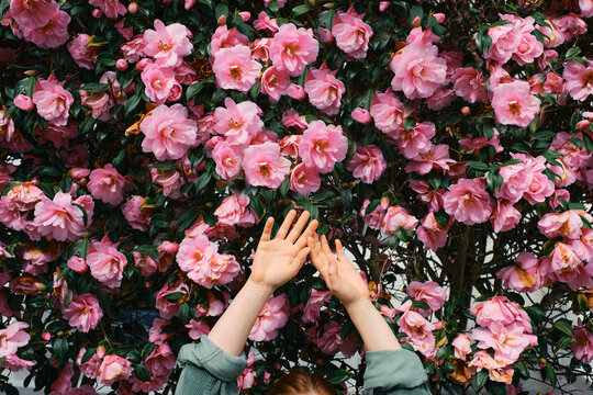 Woman with arms raised in front of flowers
