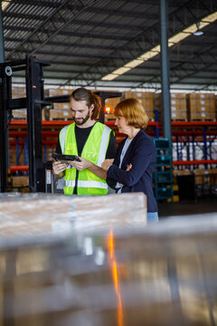 Manager and colleague discussing over tablet PC in factory
