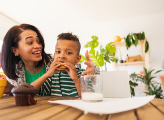 Boy eating biscuits by mother at home