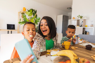 Happy boy having breakfast taking selfie with family at home