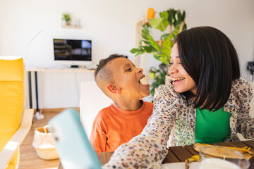 Happy mother taking selfie with son eating banana at home