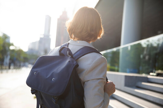 Businesswoman with brown hair wearing backpack on sunny day