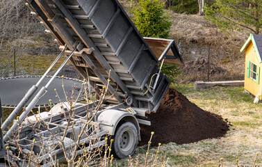 Delivery truck pouring top grade black garden soil from box to home garden in spring. © FotoHelin
