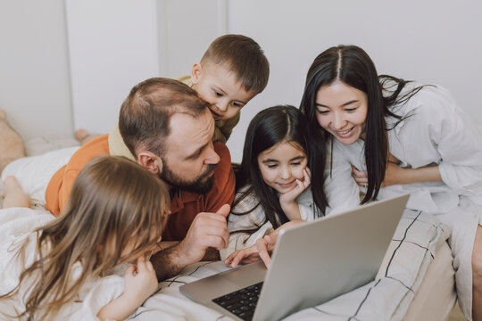 Happy family using laptop in bedroom at home