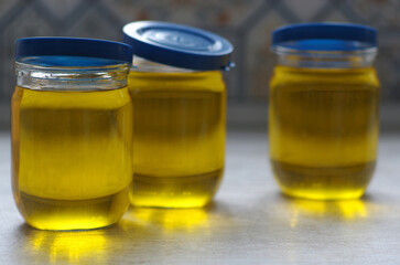 Vegetable oil in glass jars on a neutral background. Selective focus.