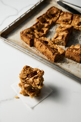 Stack of squares of Blondie cookies with pecan nuts on white marble countertop. White chocolate sweet and tasty, chewy cookie bars. 