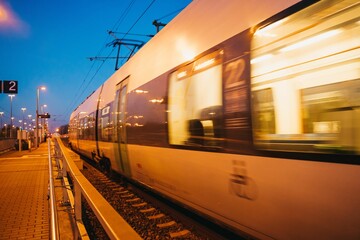 Long exposure of a train in motion captured at a train station in the evening lights