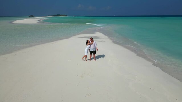 Aerial view of happy couple in love in white clothes spending great time together on Maldives