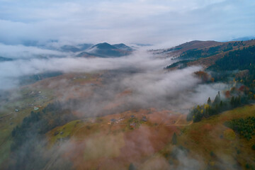 Fog spreads over the mountains at dawn. The sun rises on the horizon. Carpathians in the morning. Aerial drone view.
